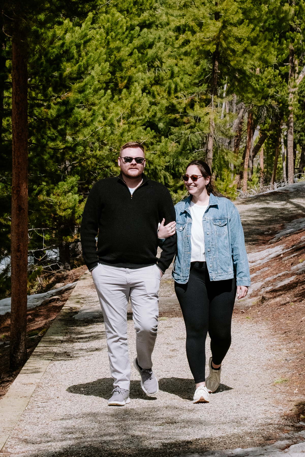 Engaged couple walking hand-in-hand on a forest path